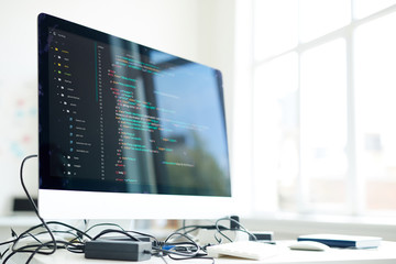 workplace of modern programmer with computer monitor, coded data on its screen and generator with ca