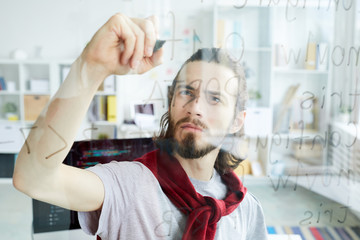 Wall Mural - serious and clever young man standing by board and writing codes with highlighter