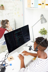 Wall Mural - Contemporary programmer in headset analyzing or decoding data in computer and talking to clients in office