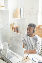 Wall Mural - Serious and concentrated young it-manager sitting in front of computer monitor and answering questions of online clients