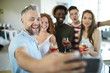 © pressmaster - Happy man and his friends with drinks posing for selfie while enjoying home party