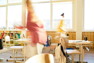 Foolishness at school break: unrecognizable students running over class and having fun at break in classroom