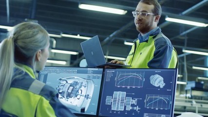 Fototapete - At the Factory: Male and Female Mechanical Engineers Use Laptop and Personal Computer while Talking. Screen Shows 3D Engine Concept made with CAD Software.