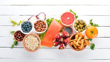 Wall Mural - A set of healthy food. Fish, nuts, protein, berries, vegetables and fruits. On a white background. Top view. Free space for text.
