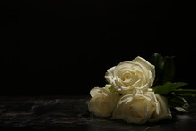 Beautiful White Roses On Table Against Black Background. Funeral Symbol