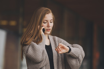 Closeup portrait, young woman in gray business suit blazer talking on cell phone concerned about running out of time on watch, isolated indoors office background