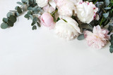 Styled stock photo. Decorative still life floral composition. Wedding or birthday bouquet of pink and white peony flowers and eucalyptus branches. White table background. Flat lay, top view.