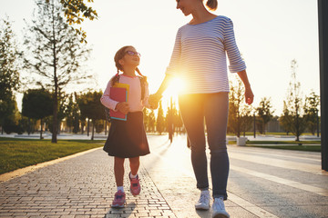 first day at school. mother leads  little child school girl in first grade.