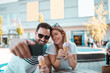 © Nebojsa - Young man with sunglasses is taking selfie with his girlfriend while they having ice-cream outdoors