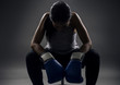 © Innovated Captures - Black female wearing boxing gloves looking angry as a boxer, MMA fighter or self defense trainer sitting after working out.  She is portraying female strength and determination.