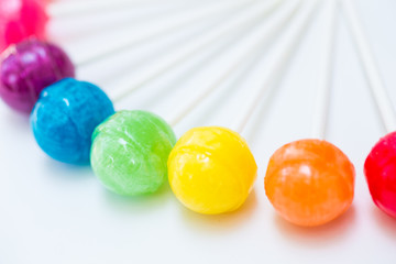 Rainbow design of sweet colorful lollipops against white background 