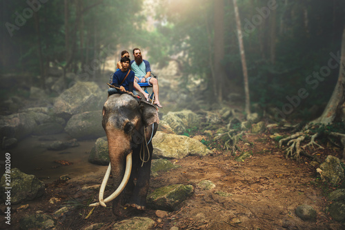 Fotografia tourist couple riding elephant through thai jungle by river on koh samui thailan