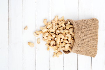 Wall Mural - Pile of cashew nuts in sackcloth pouch on white wooden desk.