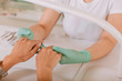 © Viacheslav Yakobchuk - Looking at hands. Nail artist wearing bright gloves looking at hands of her client coming to her beauty salon