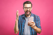 © denis_vermenko - I'm a winner! Happy man holding smartphone and celebrating his success over pink background.