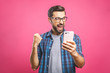 © denis_vermenko - I'm a winner! Happy man holding smartphone and celebrating his success over pink background.