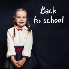 cute child little girl in school uniform clothes on chalk board background. back to school, elementa