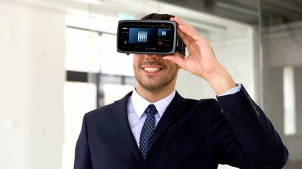 Wall Mural - business, technology and augmented reality concept - businessman with vr headset and cube 3d rendering on virtual screen at office