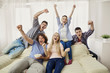 © Studio Romantic - A group of friends of fans watching a sports TV sitting on a sofa in the room.