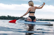 © LIGHTFIELD STUDIOS - back view of girl in bikini surfing on paddle board on river