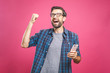 © denis_vermenko - I'm a winner! Happy man holding smartphone and celebrating his success over pink background.