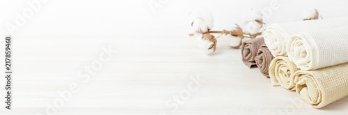 Fotomural Multicolored clean towels with a branch of cotton on a light wooden background with copy space
