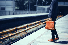 Businessman In Suit Standing At Empty Train Platform. Cropped Picture Of Gentelmen In Suit With Brown Case Standning At Metro Station And Waiting For Train To Get To His Work.