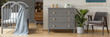 A gray, scandi style dresser with crown-shaped handles in a bright, child bedroom interior with gray, wooden furniture