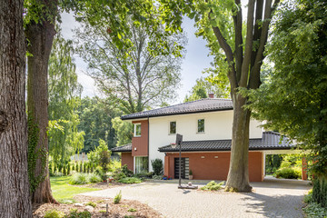 Wall Mural - Real photo of an entrance to a house with a basketball playground, trees and bushes