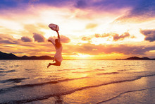 Asia Woman Jumping On The Beach In Front Of The Sea With Feeling Happy And Freedom.