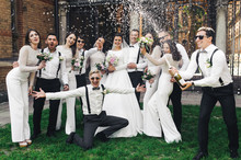 Newlyweds And Friends Open A Bottle Of Champagne Posing On The Green Lawn