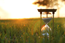 Hourglass In The Grass Time During Sunset. Vintage Style.