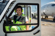 © Yakobchuk Olena - Enjoying work. Cheerful man in headphones with microphone closing door of vehicle. Airplane on blurred background