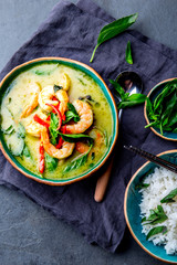 THAI SHRIMPS GREEN CURRY. Thailand tradition green curry soup with shrimps prawns and coconut milk. Green Curry in blue plate on gray background.