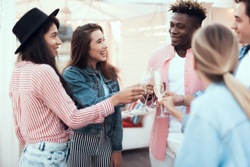 Wall Mural - Positive males and beaming women drinking glasses of champagne during party while locating inside