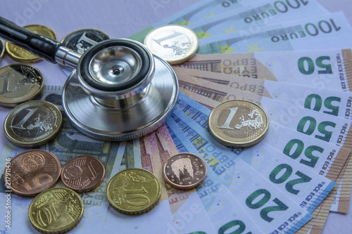 Fotografie, Obraz Coste de la medicina: estetoscopio sobre una pila de euros