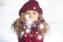 Portrait Of Young Cheerful Woman Blowing Snow Into Camera