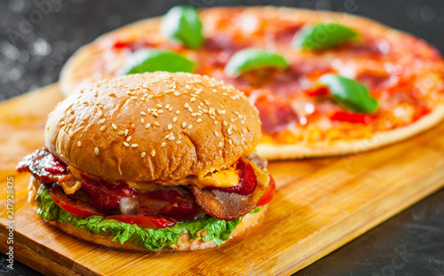 bacon cheese burger with beef patty tomato onion and Pizza with Mozzarella cheese, Ham, Tomatoes, salami, pepper, pepperoni Spices and Fresh Basil © pavel siamionov