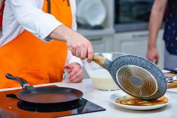 kitchen Preparation: the chef fries fresh pancakes in two pans