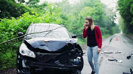 Wall Mural - Young frustrated woman making a phone call after a car accident.