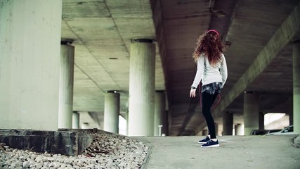 Sticker - Beautiful young woman with headphones dancing under the bridge in the city.