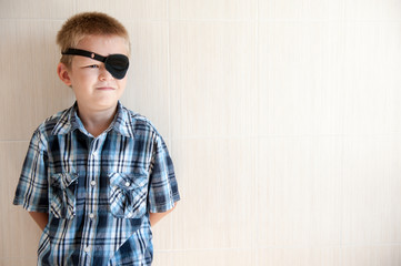 happy blond child with black medical patch occluder on eye
