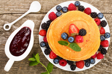 Wall Mural - Pancakes stack with different berries isolated on white background. Top view. Flat lay