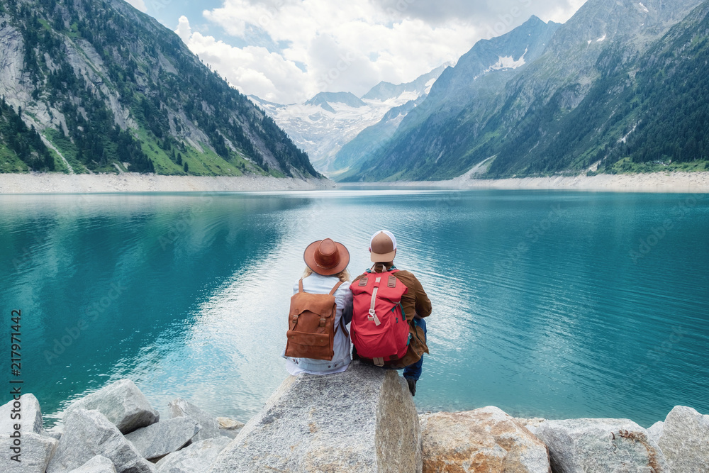 Travelers couple look at the mountain lake. Travel and active life concept with team. Adventure and travel in the mountains region in the Austria - obrazy, fototapety, plakaty 