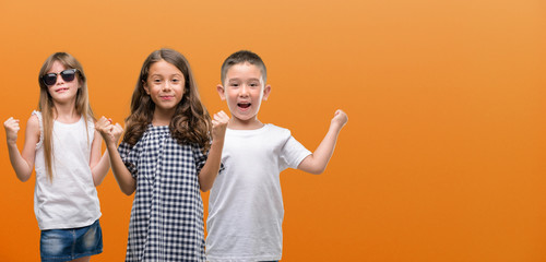 Sticker - Group of boy and girls kids over orange background screaming proud and celebrating victory and success very excited, cheering emotion