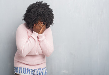 Sticker - Young african american plus size woman over grey grunge wall wearing winter sweater with sad expression covering face with hands while crying. Depression concept.