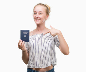 Sticker - Blonde teenager woman holding passport of Germany with surprise face pointing finger to himself