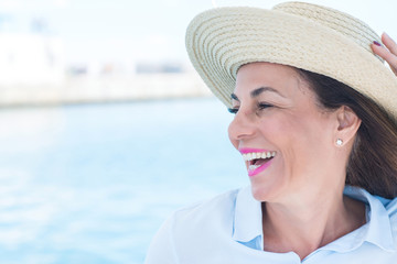 Beautiful middle age woman traveling on sailboat and smiling happy and confident.