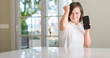 © Krakenimages.com - Down syndrome woman at home using smartphone annoyed and frustrated shouting with anger, crazy and yelling with raised hand, anger concept