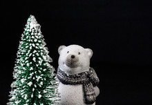Toy Polar Bear On A Black Background Next To A Christmas Tree